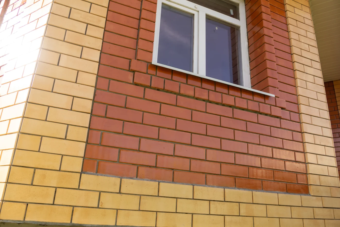 An up-close view of brown and red brick on a house with white windows.