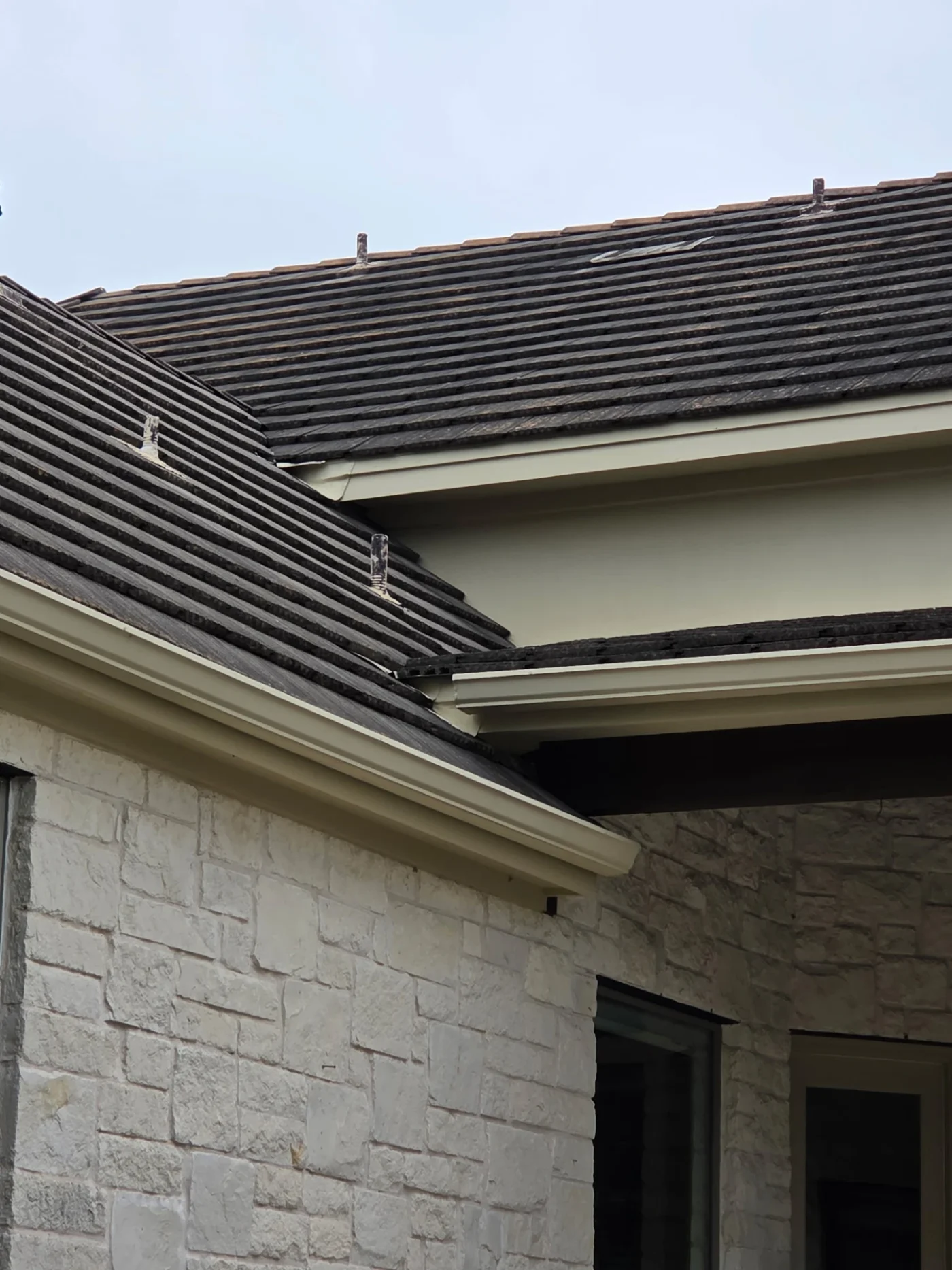 A close-up view of a concrete tile roof on a stone house.