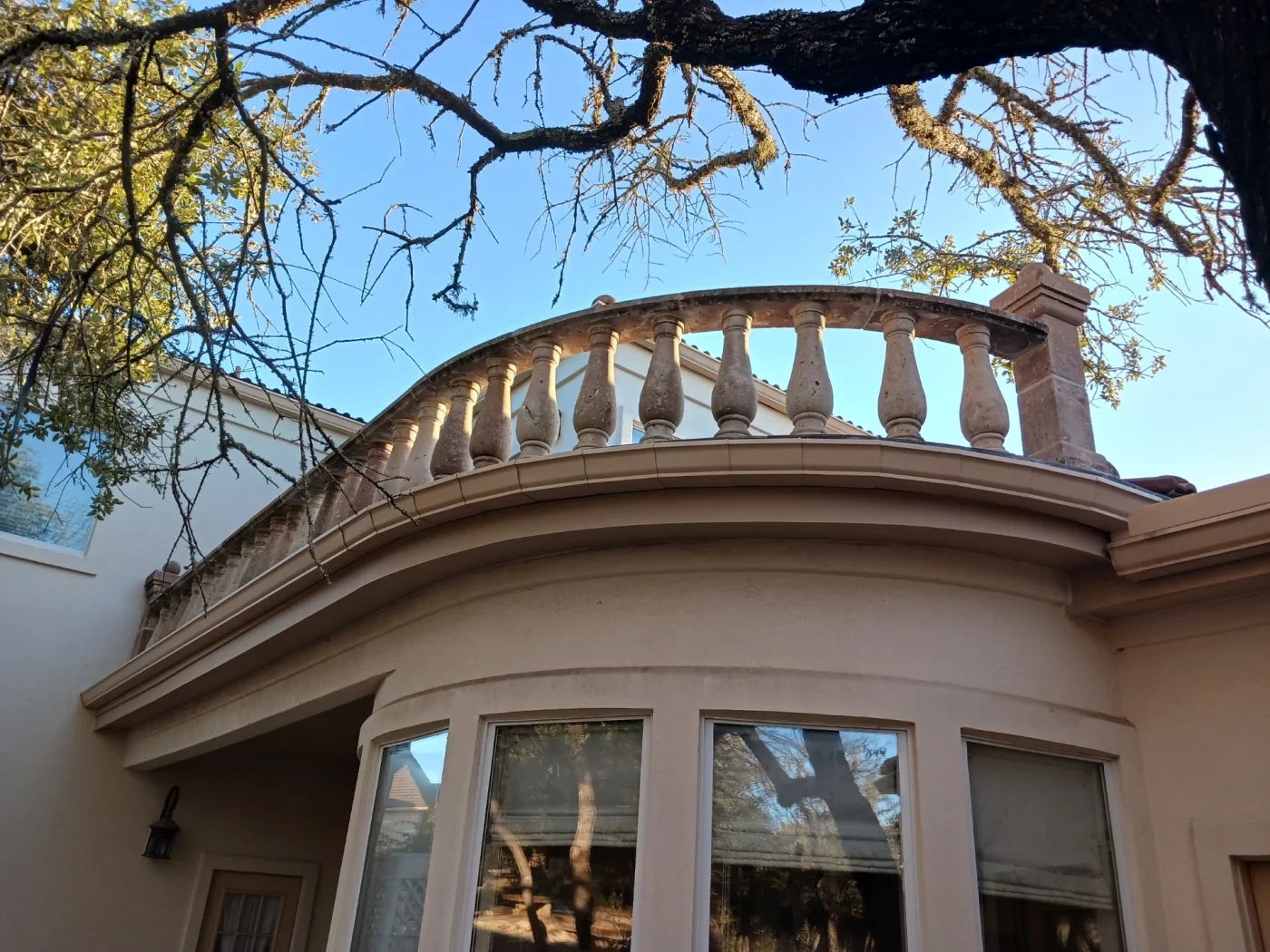 A close-up view of a stucco house with white windows.