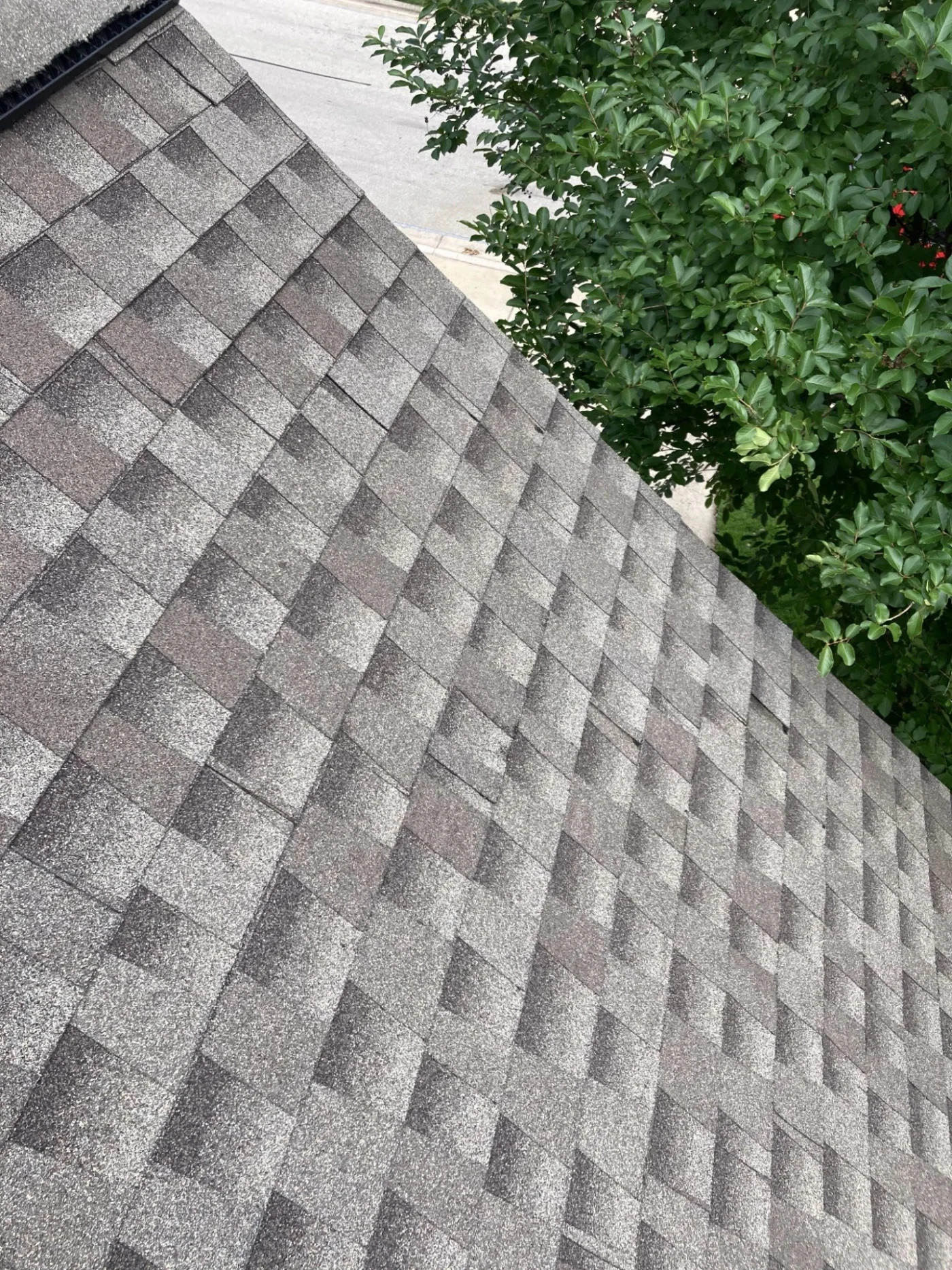 Looking up at a residential stone home reveals a curved upper balcony with a detailed stone balustrade railing that may require professional masonry repair.