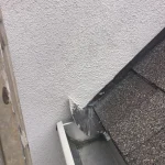 Detailed stucco repair seals the wall connection along the roof flashing and gutter edge to prevent water leaks.
