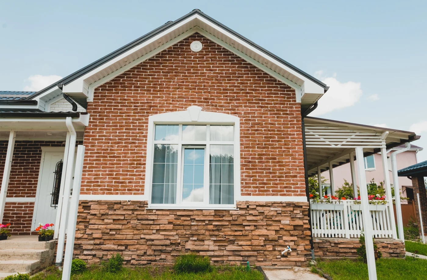 Durable Roofing Services In Belterra, TX | Wolfpack Roofing An upward view at a gray house with white windows, white trim, and an asphalt shingle roof.